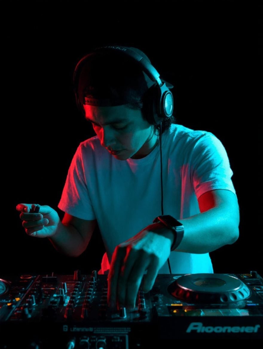 Dhystrukto mezclando en los CDJs bajo luces rojas y turquesa